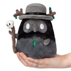 a person holding a stuffed animal with a hat on it's head and a skull in the other hand