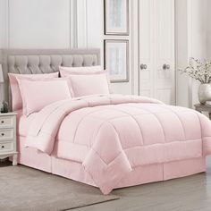 a bed with pink comforter and pillows in a room