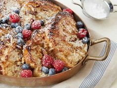 french toast casserole topped with berries and powdered sugar in a skillet