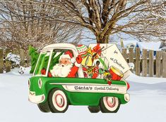 a green and white truck with santa clause on it's back in the snow