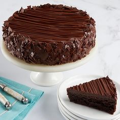 a chocolate cake sitting on top of a white plate next to a knife and fork