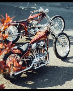 an orange and black motorcycle parked on top of a parking lot next to some trees