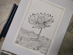 a drawing of a flower on paper next to a pen