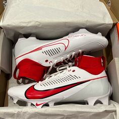 a pair of white and red soccer cleats are in a box on the floor