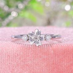 ✧･ﾟ: *✧･ﾟ:* Welcome to Charles Davin Jewelry*:･ﾟ･ﾟ✧ Moissanite - a gemstone known to bring in luck in someone's life, the user can give off a look of elegance. You can give your special someone luck whilst showing your love to them.  ✶Material: 10K/ 14K/ 18K ✶Main Stone: Moissanite; 2.0mm-2pcs ✶Side Stone: - ✶Color: D Colorless ✶Clarity: VVS1 ✶Width of band: 1.5mm ✶Thickness of band: 1.2mm OR  ✶Side Stone: Diamond ✶Color: F-G ✶Clarity: SI1 PRODUCTION TIME My team of jewelry artisans and I are ec Fine Jewelry White Gold Gemstone Flower Ring, Anniversary White Gold Flower Ring With Gemstone, Flower Shaped Gemstone Promise Ring, Flower Shaped Gemstone Ring For Promises, Flower Ring With Diamond Accents For Anniversary, Delicate White Gemstone Rings, Exquisite Flower Shaped Gemstone Rings, Elegant Flower Cluster Ring As Gift, Elegant Flower Cluster Ring Gift