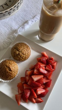 two muffins and strawberries on a plate next to a glass of milk