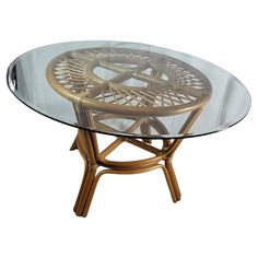 a round glass table with wooden legs and a rattan design on the top, against a white background