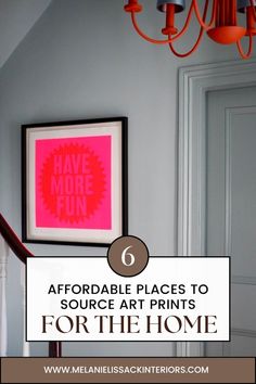 a pink poster hanging on the wall next to a chandelier and light fixture