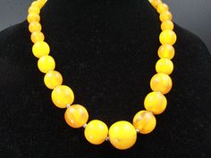 "DESCRIPTION: This vintage necklace, hailing from the 1960s, is a captivating display of mid-century fashion with its graduating array of eggyolk-colored resin beads. In excellent condition, it exudes a warm and nostalgic charm, measuring a substantial 23\" in length. The beads range from a dainty 12mm to an eye-catching 26mm, making this necklace a versatile and stylish accessory that adds a pop of vintage flair to any ensemble. NOTE: Insurance fee and handling fee are included in the shipping fee for items worth $400 and above. SHIPPING: The shipping fee includes postage, packaging, and handling. We typically ship items within one day of receiving payment. If you're buying multiple items, we offer combined shipping, but please wait for your invoice before checking out. For international Yellow Costume Jewelry Necklace For Formal Occasions, Yellow Costume Jewelry Necklace For Formal Events, Vintage Yellow Single Strand Jewelry, Retro Necklaces With Large Round Beads, Vintage Polished Yellow Beads Jewelry, Vintage Yellow Jewelry With Polished Beads, Vintage Orange Round Bead Necklace, Vintage Orange Round Beads Necklace, Vintage Yellow Round Bead Necklaces