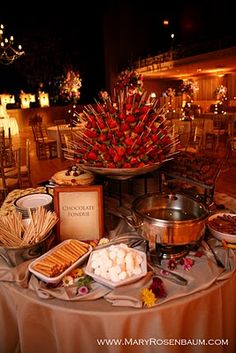 a table topped with lots of food on top of a white table cloth covered table