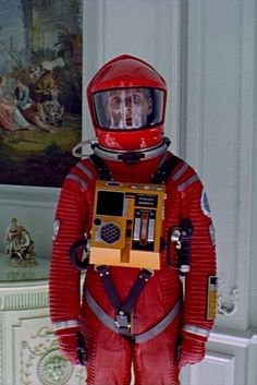 a man in a red space suit standing next to a painting