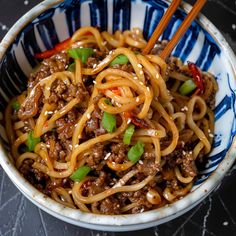 a close up of a bowl of noodles with meat and green onions on the side