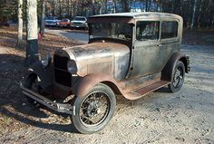 an old, rusty car is parked in the dirt