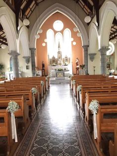 the inside of a church with pews and flowers on each side of the aisle