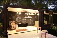 a living room with a chalkboard on the wall next to a chair and table