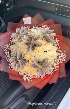 a bouquet of flowers sitting in the center of a car dash board with money attached to it