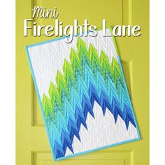 the front cover of mini firelight lane quilt pattern book, featuring a blue and green zigzag design