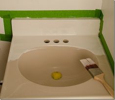 a white sink with a brush in it and green paint on the wall behind it