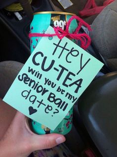 a hand holding a can with a sign attached to it that says hey cuta will you buy my senior bail?