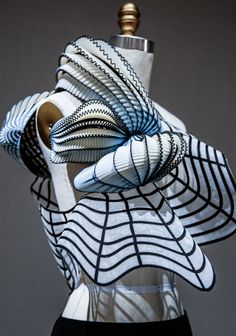 a mannequin's head is covered in white and black fabric with an intricate design