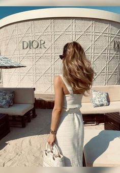 a woman in a white dress is standing on the beach with her back to the camera