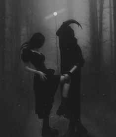 two women dressed in black standing in the woods