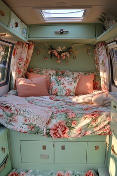 the interior of a camper with floral bedspread and pink pillows on it