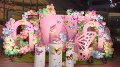 balloons and decorations are displayed in front of a pink backdrop at a children's birthday party