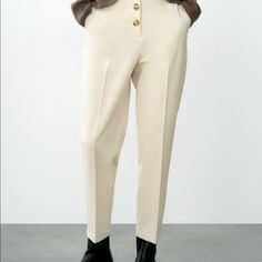 High Waist Cigarette Pants With Front Pockets And Back Patch Pockets. Front Closure With Contrast Buttons. Color Cream Beige Ankle-length Pants With Button Closure, Office Pants With Button Closure And Tapered Leg, Beige Tapered Leg Bottoms With Button Closure, Beige Workwear Pants With Button Closure, Chic Office Wear Bottoms With Button Closure, Chic Tapered-leg Pants With Button Closure, High Waist Cream Bottoms For Office, Chic Bottoms With Button Closure For Office Wear, Beige Tapered Leg Pants With Button Closure