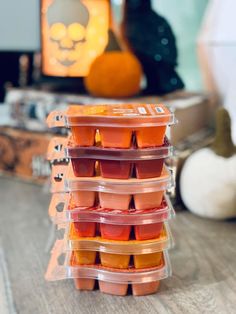 several plastic containers filled with food sitting on top of a wooden table next to pumpkins