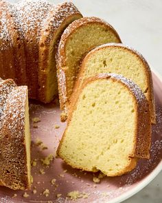 there is a cake that has been sliced and served on a pink plate with powdered sugar sprinkled around it