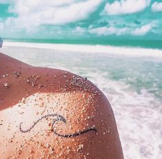 the back of a person's head with writing on it and water in the background