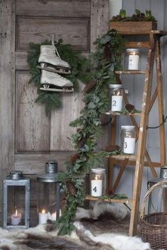 a shelf filled with candles and greenery next to a wooden ladder in front of a door