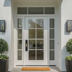 a white front door with two planters on either side and an entry way leading to it