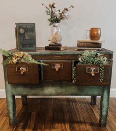 an old table with drawers and flowers on top is decorated with greenery, leaves and other things