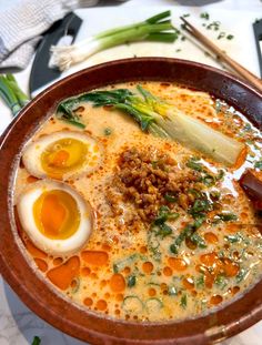 a bowl filled with soup and eggs on top of a table