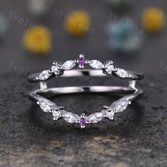 a white gold ring with amethorate and purple sapphire stones in the middle