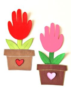 two flower pots with paper cut outs on the top and bottom one has a heart in it