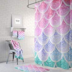 a bathroom with pink, blue and green shower curtain next to a white chair in front of a brick wall