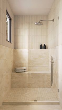 a white tiled bathroom with shower and window