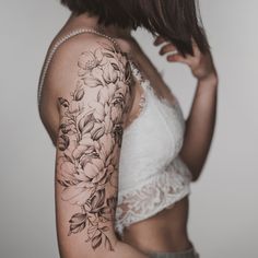 a woman's arm with flowers on it and a white bra - top in the background