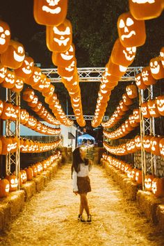 a woman is standing in front of pumpkin lights