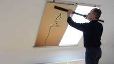 a man standing in front of a drawing on the wall with a paint roller and brush