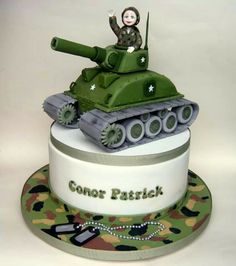 a cake with a tank on top and a person sitting on top of the tank