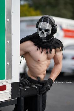 a shirtless man wearing a skull mask and bandana stands in front of a semi truck