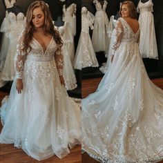 a woman standing in front of a mirror wearing a wedding dress with long sleeves and open back