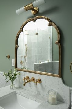 a bathroom sink under a large mirror next to a white counter top with gold faucets