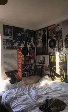 an unmade bed with posters on the wall