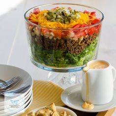 a glass bowl filled with salad next to two plates of food