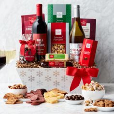 the wine and snacks gift basket is filled with red wine, nuts, crackers, chocolates, and more